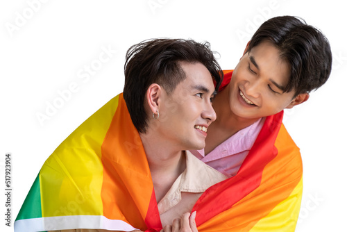 Portrait of cute Asian LGBT homosexual men or gay couple smiling and embracing, covered with pride rainbow flag, on white background. Looking at each other.
