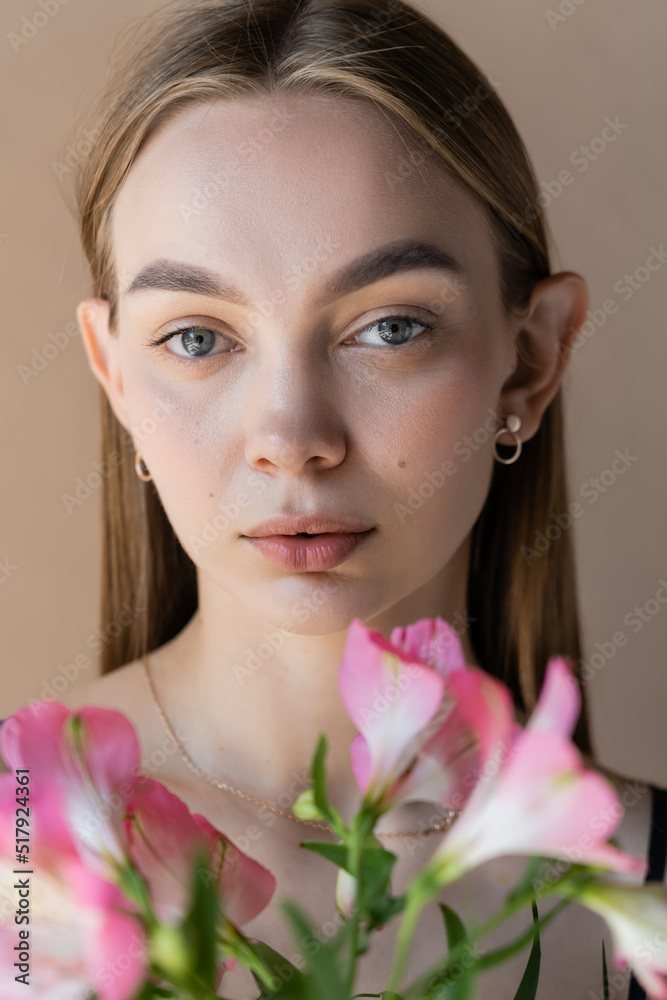 portrait of young woman with clean skin and natural makeup looking at camera isolated on beige. portrait of young woman with clean skin and natural makeup looking at camera isolated on beige.