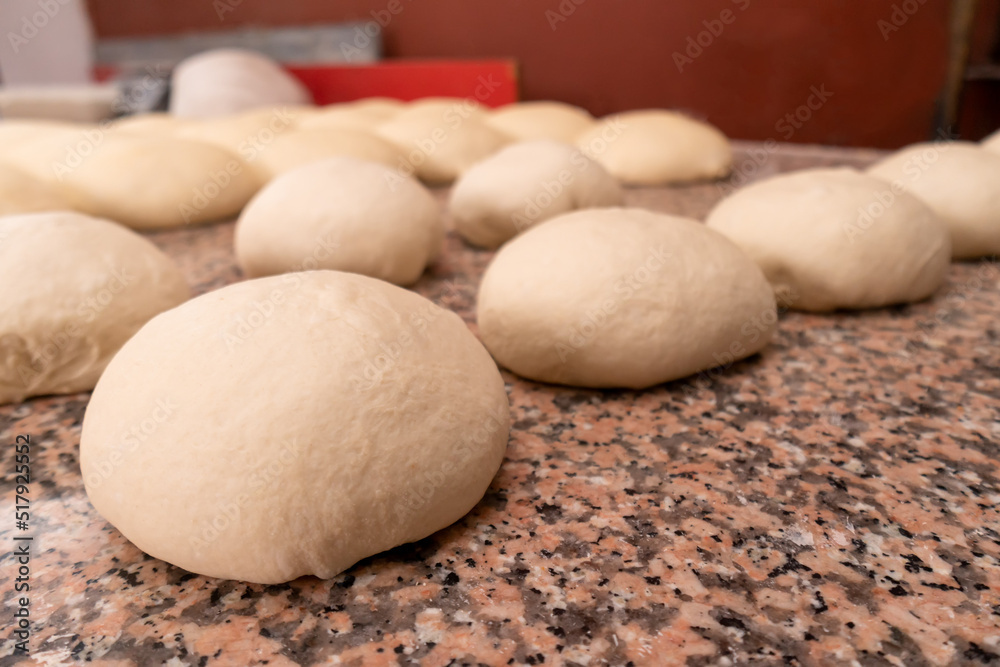 Close-up of balls of fresh raw dough for baking buns or other wheat flour products, on the kitchen table. Blank for baking Close-up of balls of fresh raw dough for baking buns or other wheat flour products, on the kitchen table. Blank for baking