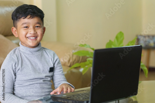The Asian boy focusing working on laptop and have a cute smile