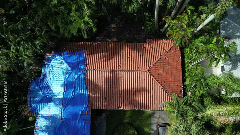 Aerial view of a roof that needs repairs. Looking down from above at a roof covered with a tarp waiting for the roofing company to fix the roof.