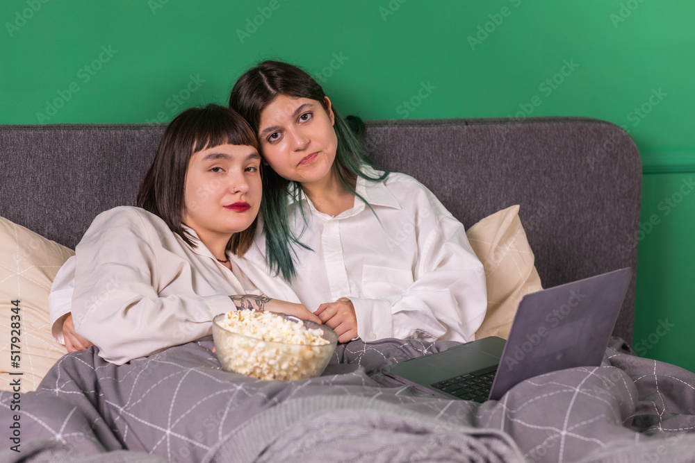 LGBT concept happy two ladies laying on the bed together and looking over the laptop and smiling large enjoy the morning together