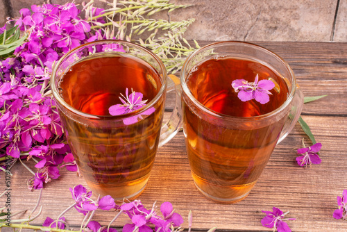 Two transparent mugs of a drink  decoction  from the leaves and flowers of the medicinal plant ivan-tea  kipreya  epilobium  on a wooden background close-up. Traditional  folk  medicine.