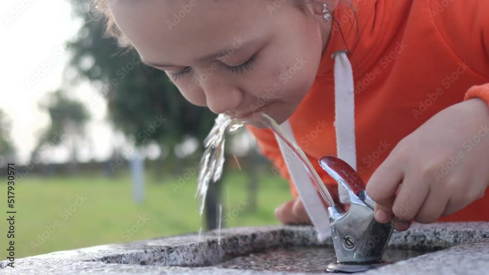 Close-up portrait of 9 years child girl drinking water from drinking fountain at city park, 4k