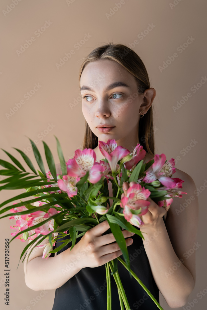 charming woman with bouquet of pink alstroemeria looking away isolated on beige. charming woman with bouquet of pink alstroemeria looking away isolated on beige.