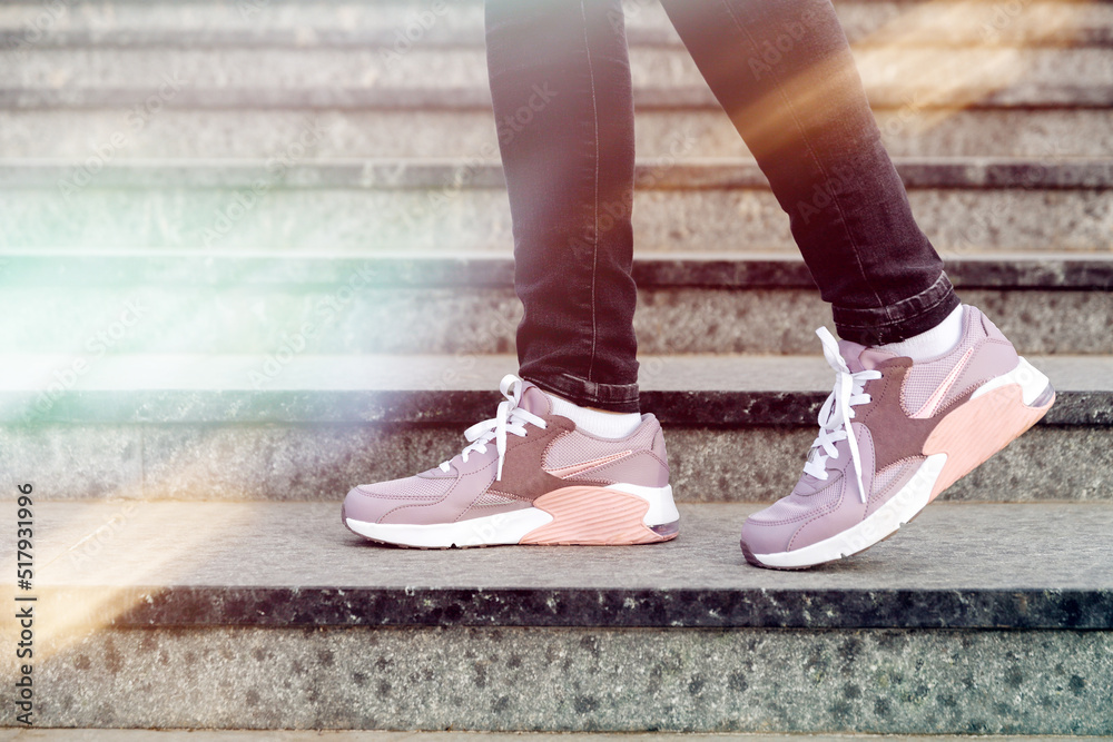cropped image of female legs in shoes. Woman in pink sneakers descend stairs cropped image of female legs in shoes. Woman in pink sneakers descend stairs