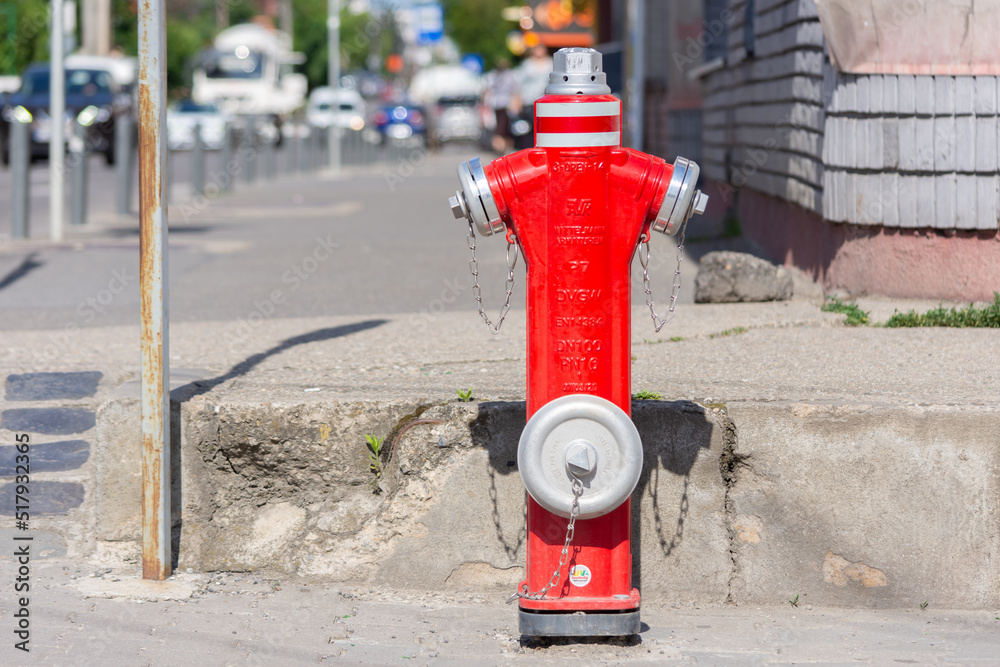 Front side of a hydrant made of metallic material being on a sidewalk in a city. Blurred background Front side of a hydrant made of metallic material being on a sidewalk in a city. Blurred background
