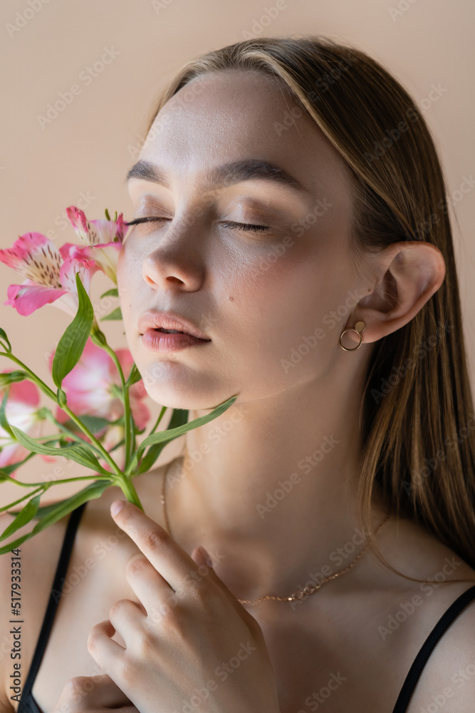 sensual woman with closed eyes and perfect skin smelling alstroemeria flowers isolated on beige. sensual woman with closed eyes and perfect skin smelling alstroemeria flowers isolated on beige.