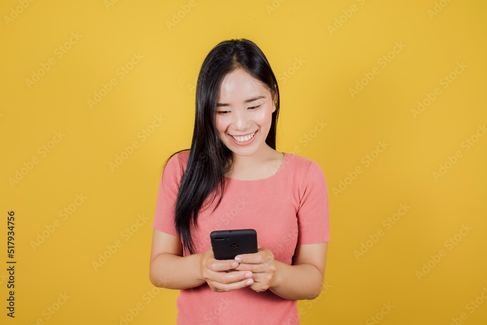 Portrait of smiling asian woman using a smartphone on yellow background Portrait of smiling asian woman using a smartphone on yellow background