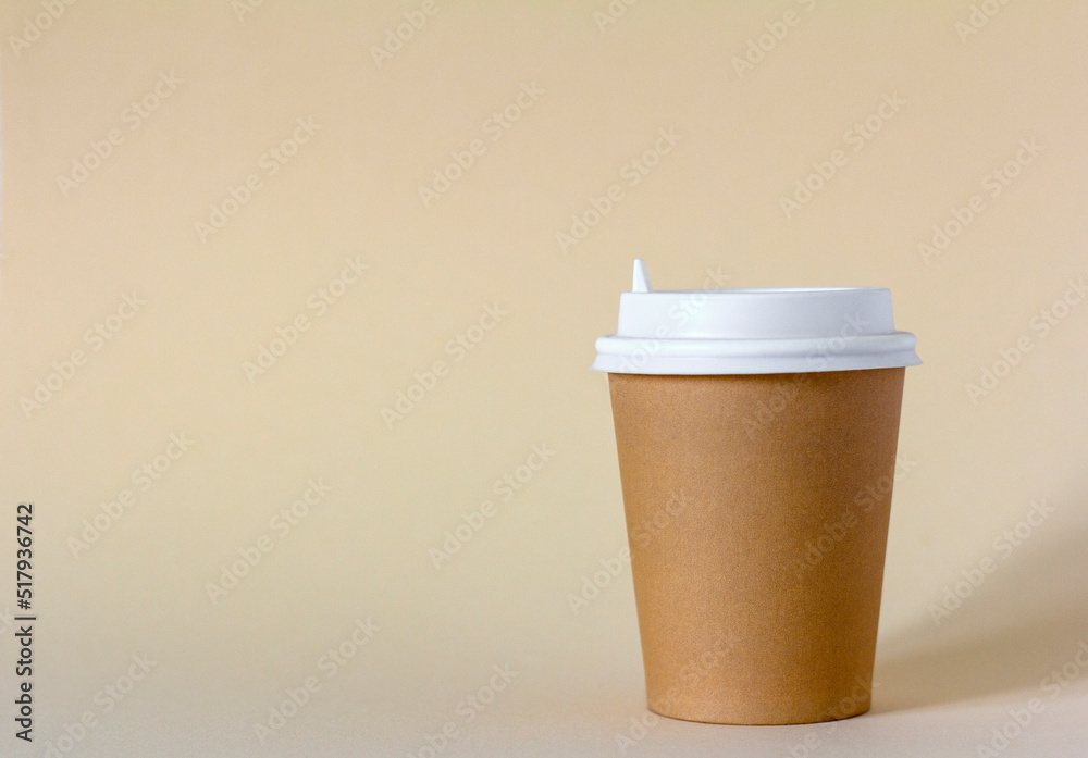 A paper cup for takeaway coffee on a light beige background.