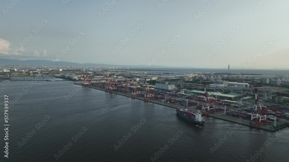 Container ship maneuvers into docking position under loading cranes Container ship maneuvers into docking position under loading cranes