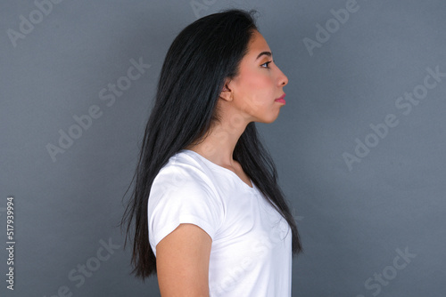 Profile of smiling young beautiful brunette woman wearing white t-shirt over grey background with healthy skin, has contemplative expression, ready to have outdoor walk.