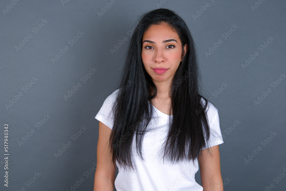Happy young beautiful brunette woman wearing white t-shirt over grey background looking at camera with charming cute smile. Happy young beautiful brunette woman wearing white t-shirt over grey background looking at camera with charming cute smile.