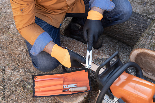Sharpening a chainsaw Close up on a man sharpening a chainsaw chain with file.