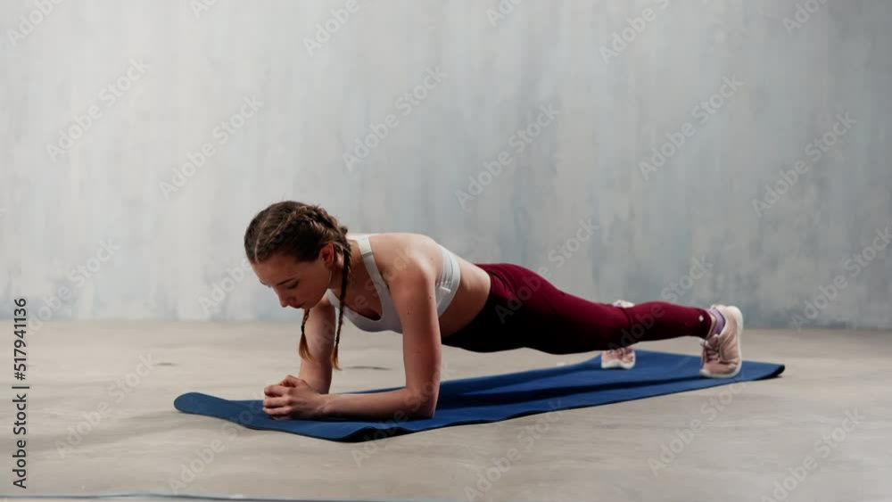 Sports woman in fashion sport clothes working out against grey wall. Sports woman in fashion sport clothes working out against grey wall.