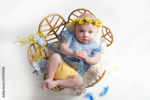 Ukrainian newborn baby girl dressed in elegant clothes in the colors of the Ukrainian flag. beautiful clothes and flowers on the head hair. Stylish clothes in trendy Ukraine colors