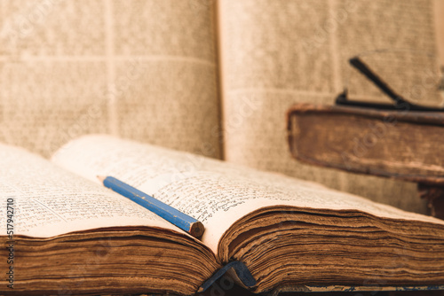 Obraz na płótnie Old worn shabby jewish books in leather binding and open blurred Torah in the background. Closeup. Selective focus. w salonie