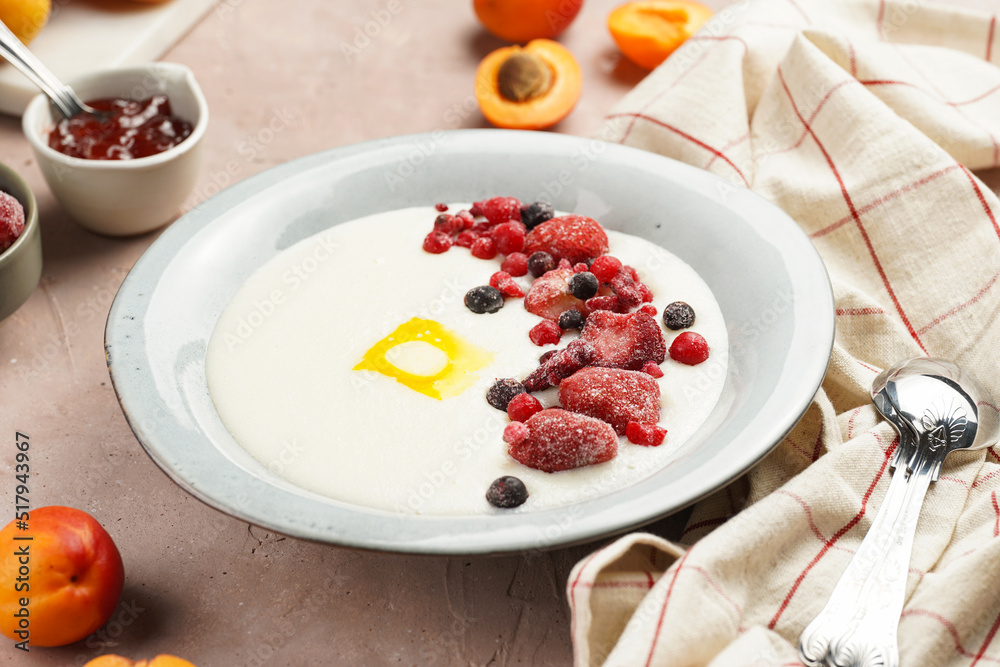 Traditional breakfast semolina porridge - creamy pudding with butter, frozen berries and fresh apricots in a grey plate Traditional breakfast semolina porridge - creamy pudding with butter, frozen berries and fresh apricots in a grey plate