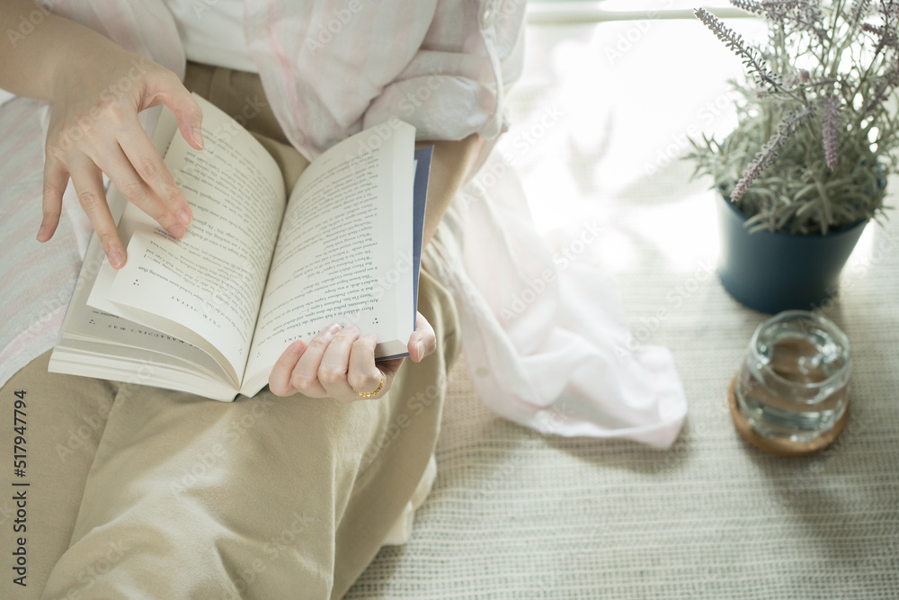 still at home concept with asian woman reading book in her living room