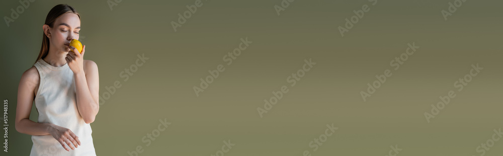 woman with closed eyes smelling fresh aromatic lemon isolated on green, banner. woman with closed eyes smelling fresh aromatic lemon isolated on green, banner.