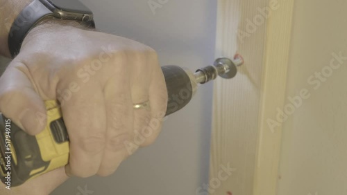 Battery powered drill used to screw wood frame to wall