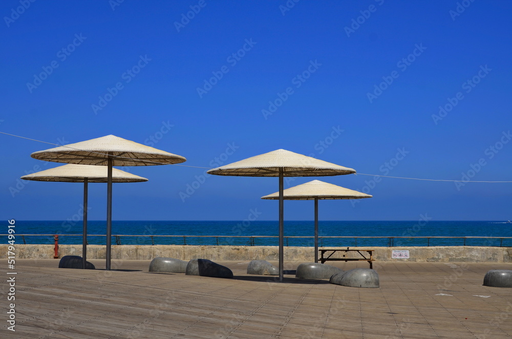 Embankment of Tel Aviv. City port. Wooden flooring and cozy umbrellas over the benches. sea view