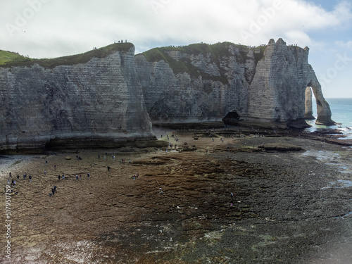 Low tide period and view on ocean bed and chalk cliffs of Porte d'Aval arch in Etretat, Normandy, France. Tourists destination.
