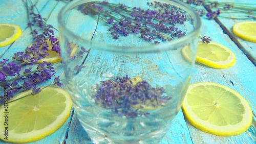 Preparation of lemonade from fresh lavender flowers, lemon on a wooden vintage background. A stream of boiling water is poured into a glass. Slow motion. photo