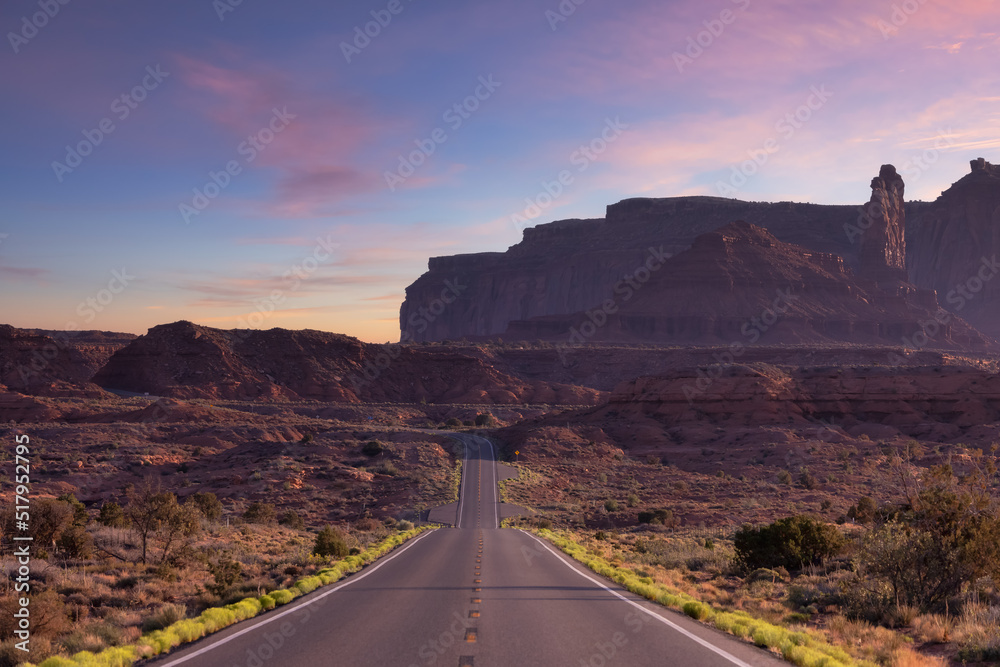 Scenic Road in the Dry Desert with Red Rocky Mountains in Background. Oljato-Monument Valley, Utah, United States. Sunset Sky Art Render