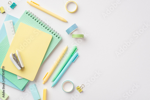 School supplies concept. Top view photo of stationery copybooks pens stapler ruler binder clips adhesive tape and erasers on isolated white background