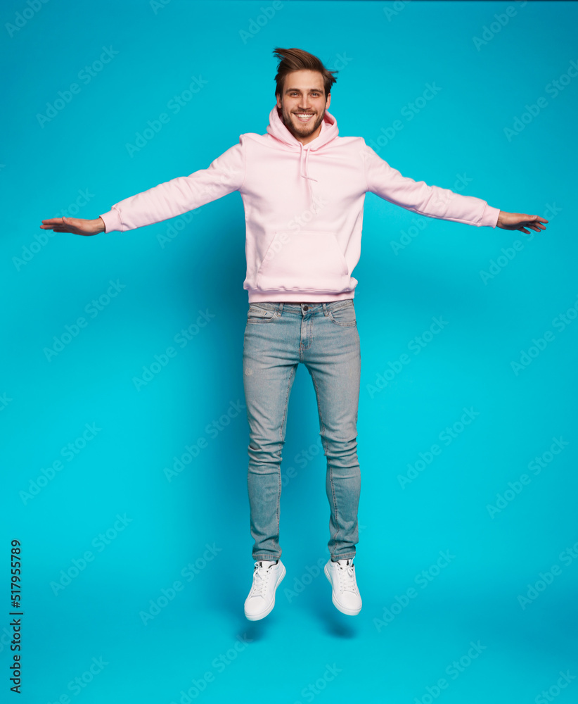 Full size photo of young happy excited smiling positive man jumping isolated on light blue color background. Full size photo of young happy excited smiling positive man jumping isolated on light blue color background.