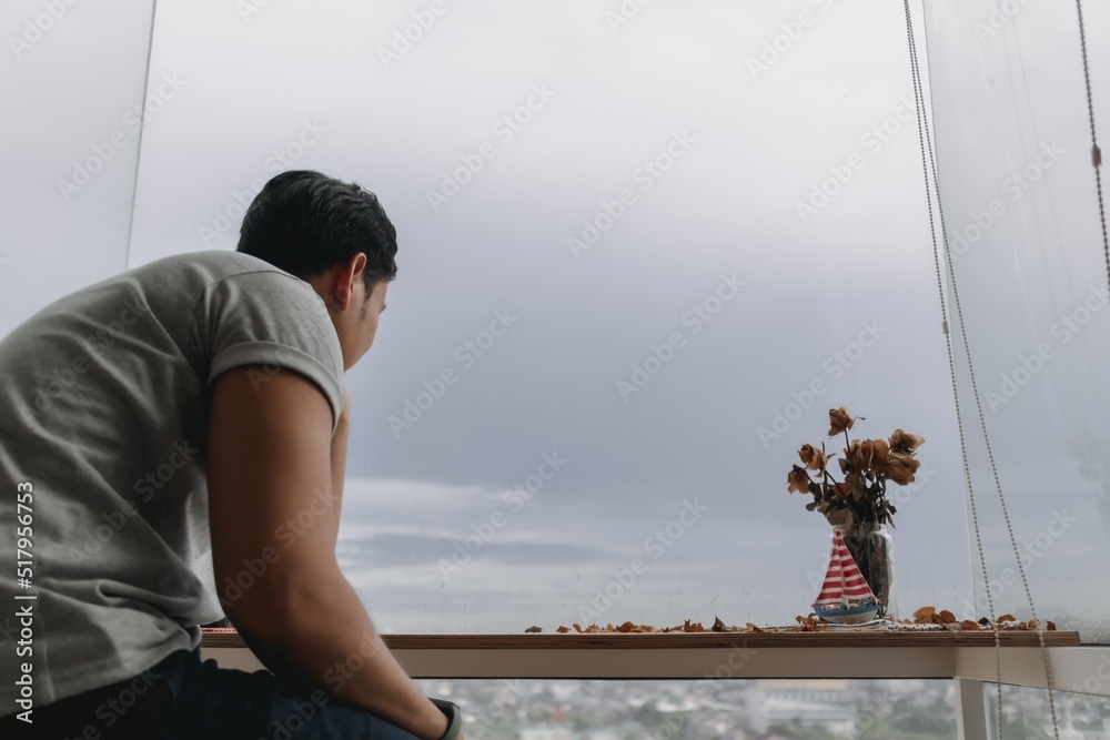 Lonely asian man sits by the windows looking at the rainy cloud. Lonely asian man sits by the windows looking at the rainy cloud.