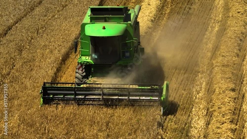 World food crisis. Green modern harvester in a field of ripening wheat. Filmed from a drone with a telephoto lens. Parallax effect.  photo