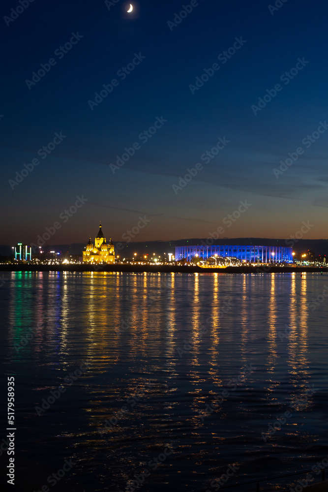 Night view of Nizhny Novgorod from the Volga River, a church, a bridge with a Russian city with illumination