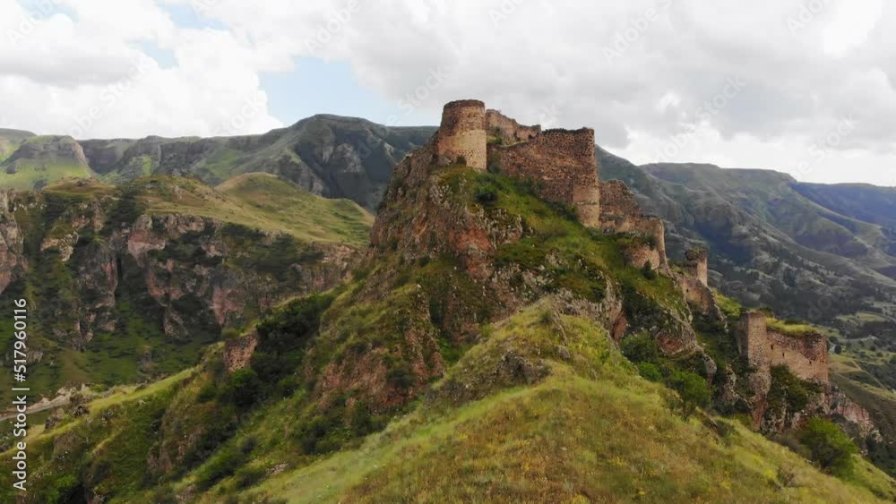 Aerial rising view dramatic landscape with historical Tmogvi fortress ruins with old wall on hilltop surrounded scenic Mtkvari river and canyon panorama Aerial rising view dramatic landscape with historical Tmogvi fortress ruins with old wall on hilltop surrounded scenic Mtkvari river and canyon panorama