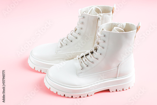 White demi-season martens boots made of eco-leather with a rough sole stand on a pink.