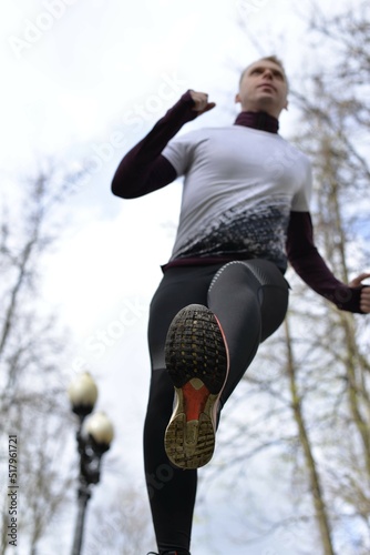 The runner steps over the camera. Active lifestyle. How does a person run. Sportswear. Good body shape.