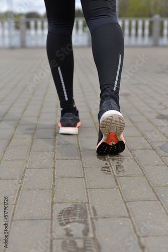 Legs of a person running on the cobblestones. The man is running. Sportswear. Healthy lifestyle. Wet footprints from shoes on the dry surface of the track.
