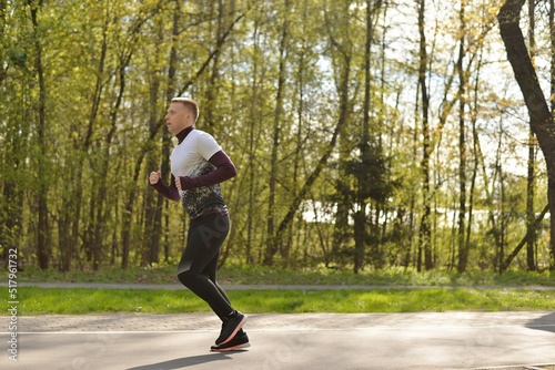 A man in sportswear is jogging. City park path. Active lifestyle. Jogging in the city.