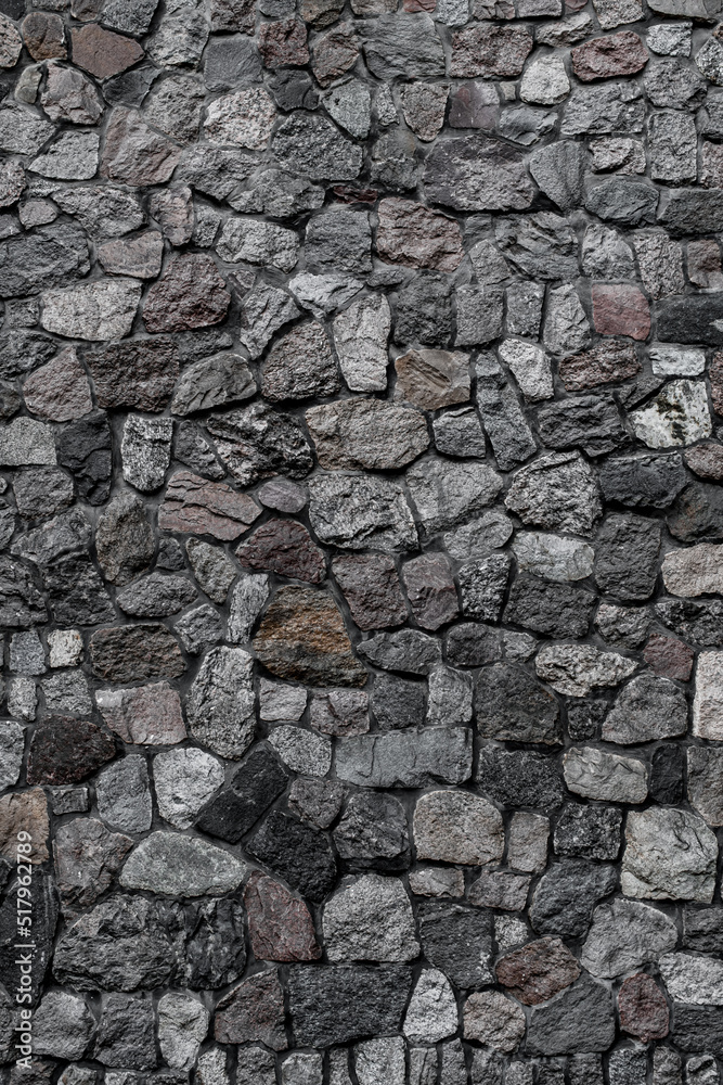 vertical view of wall with masonry of various stones. Background and texture of stone wall surface