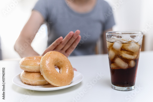 Dieting or good health concept. Young woman rejecting Junk food or unhealthy food such donut sweets or soda drink and choosing healthy food such as fresh fruit or vegetable.