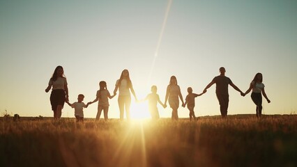 community large family in the park. a large group of people holding hands walking silhouette on nature sunset in the park. big lifestyle family kid dream concept. people in the park. large family