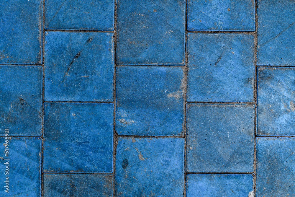 Fototapeta premium Close-up top view on texture of paving slabs covered with blue paint. Pavement tile pattern.