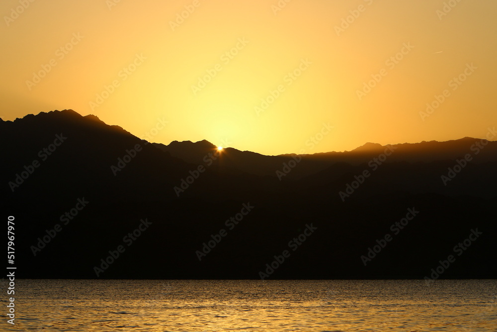 Sunrise at the Dead Sea in Israel. The sun comes out from behind the mountains in Jordan.