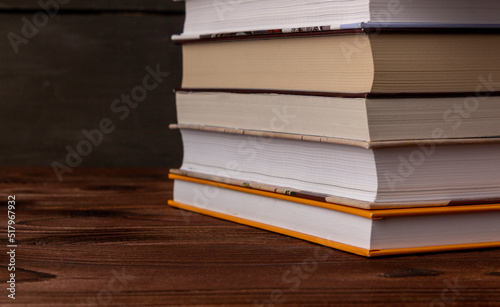 Close-up stack of books on a wooden table with space for text. Books in the library on the table. Literature about business. Novels and tales, adventures, stories. The background for design