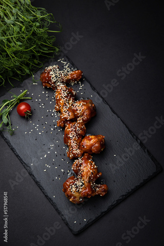 grilled chicken wings with sesame seeds and spices on black background