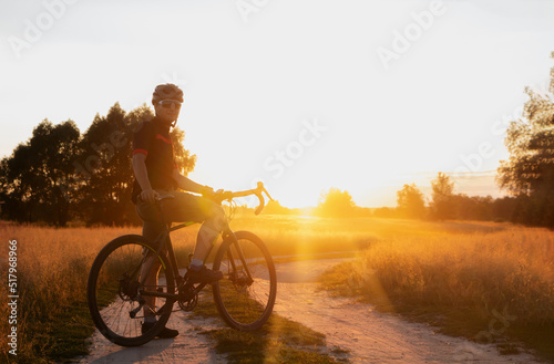 Cyclist on a countryside dirt road at sunset.