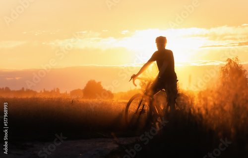Silhouette of Cyclist on a countryside dirt road at sunset.