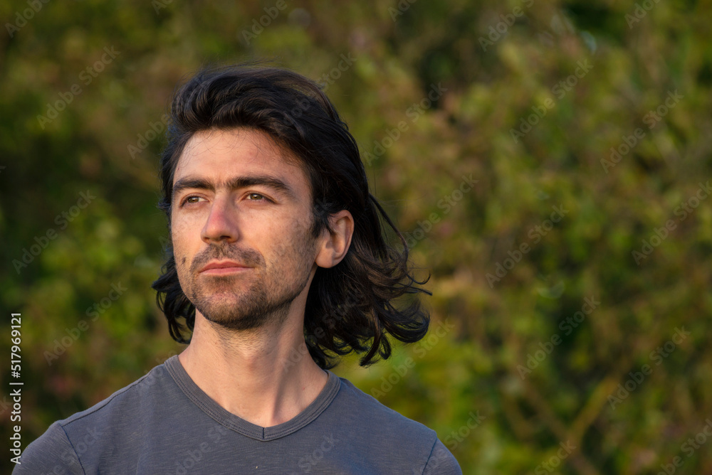 Portrait of happy young man looking at camera outdoor. beard feeling confident at sunset. Closeup nature background. summer day long hair Handsome grey shirt sexy finger up thumbs up smiling Portrait of happy young man looking at camera outdoor. beard feeling confident at sunset. Closeup nature background. summer day long hair Handsome grey shirt sexy finger up thumbs up smiling