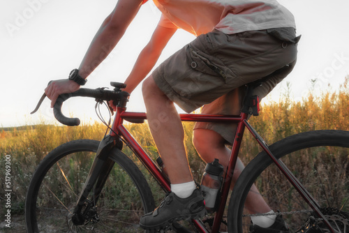 Cyclist riding in a field at sunset. Man on bicycle at sunset close up.